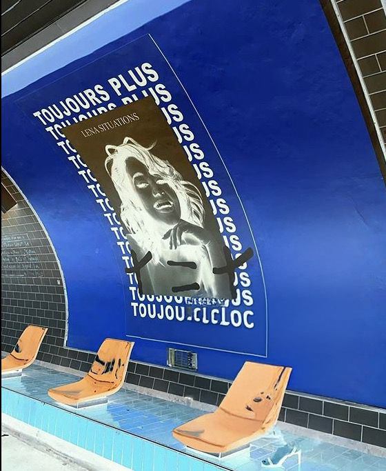 Affiche du livre ‘Toujours Plus’ en version négative, installée sur un mur bleu dans une station au style rétro avec sièges orange.